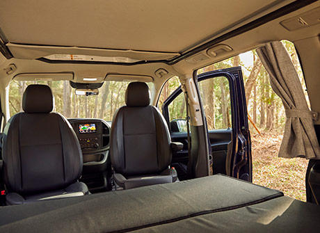 Interior view of the Metris pop top camper van, with the back-seat bench converted into a bed.